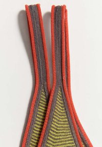 Deux sangles en tissu alignées verticalement avec des centres gris à rayures jaunes et des bords orange sur un fond clair.