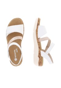 Weiße und beige Sandalen mit Kork-Blockabsätzen, ausgestattet mit weichen Riemen, Klettverschlüssen und einer gepolsterten Fußbett für Komfort.
