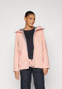 Světle růžová nepromokavá bunda s šedou kapucí, předním zipem a prostornými rukávy, nošená přes černé tričko a tmavé kalhoty.