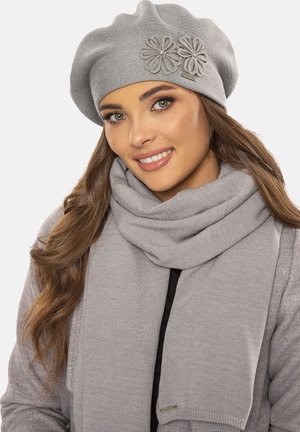 Berretto grigio con decorazioni floreali e sciarpa grigia, entrambi realizzati in morbido materiale a maglia, caratterizzati da una texture liscia e un design semplice.