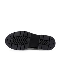 Suela de zapato de goma negra con una superficie texturizada, que presenta surcos y crestas profundas para tracción, realzada por detalles de clavos circulares.