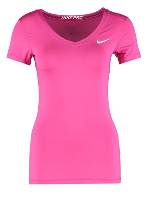 Kobieta ubrana w różową koszulkę Nike, czarne szorty z dużym białym logo Nike oraz czarne i neonowo-zielone buty do biegania, pozująca podczas chodzenia bokiem.