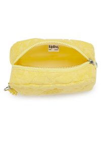 Pieni keltainen Kipling-pussi, jossa on avoin vetoketju ja tyhjät sisätilat sekä tuotemerkkilogo sisällä.