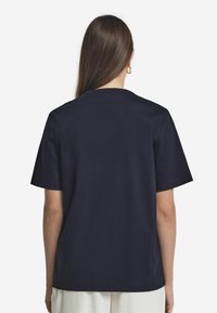 Marinblå kortärmad t-shirt i bomull med avslappnad passform. Har en enkel runda halsringning och en mjuk yta.