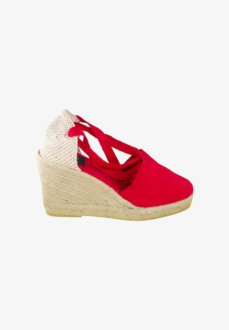 Sandalia cuña de lona roja con tacón beige tejido, tiras cruzadas en el tobillo y suela plataforma envuelta en yute sobre un fondo blanco.