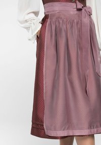 Jupe tablier bordeaux avec motif à pois, superposition légère violet clair, lien à la taille ajustable et texture de tissu lisse.