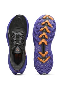 Zapatos deportivos negros con un upper texturizado, suela púrpura y acentos naranjas. Punta redondeada, cierre de cordones y un patrón de relieve pronunciado.