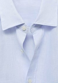 Camisa de lino azul claro con cuello clásico, que presenta dos botones blancos en el cuello. La tela tiene una sutil textura y un acabado suave.