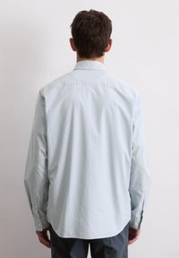 Lichtblauw overhemd met lange mouwen, voorzien van een subtiel ruitpatroon, button-down kraag en met knopen afsluitbare manchetten, gemaakt van katoen.