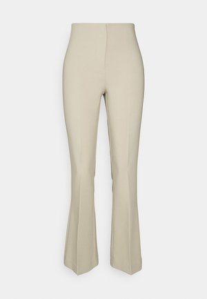 Pantalon beige taille haute avec une jambe haute ajustée et une jambe basse évasée, à l'avant lisse sans poches visibles ni ornements.