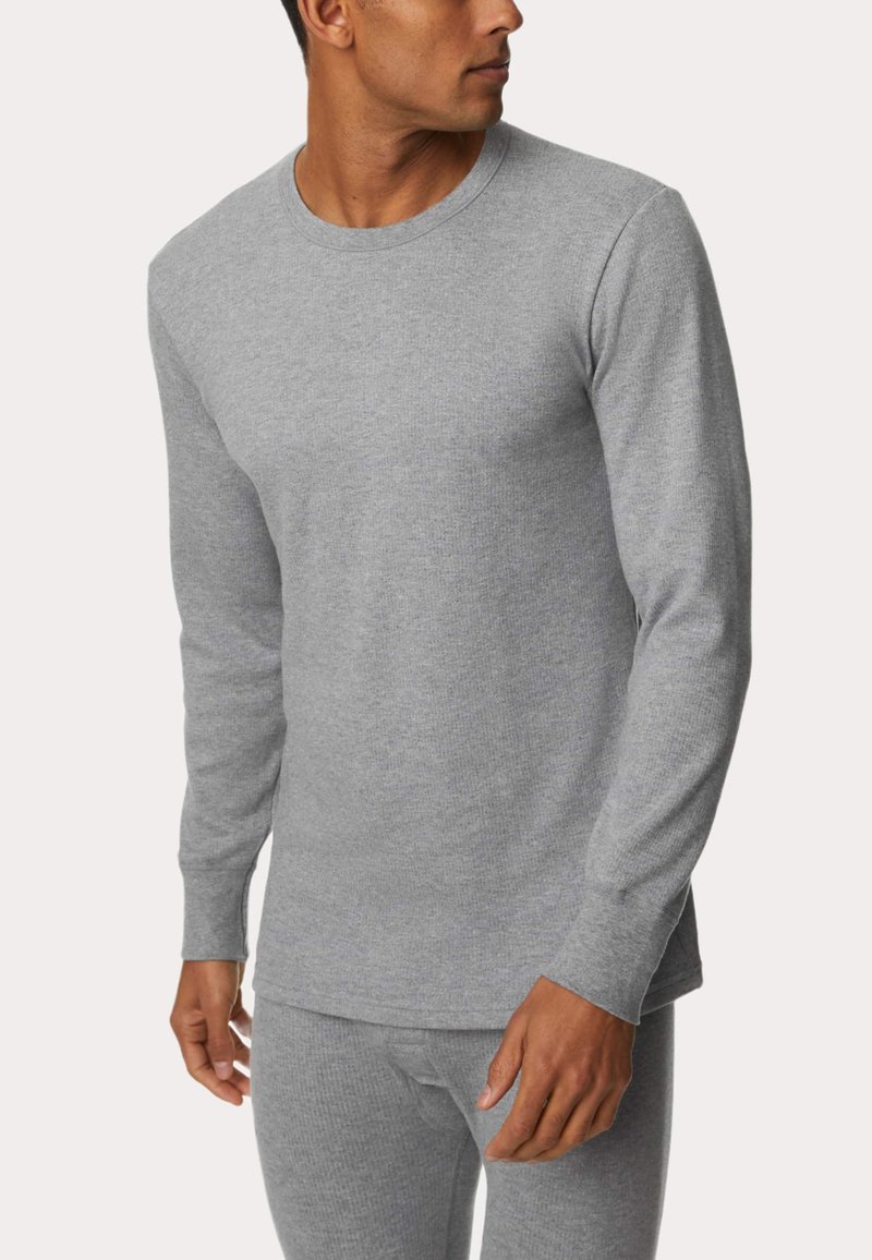 Maglia termica grigia a maniche lunghe realizzata in tessuto a coste, con scollatura a girocollo e maniche attillate, abbinata a pantaloni coordinati.