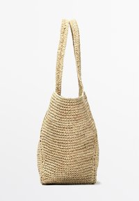 Borsa a tracolla intrecciata in paglia di colore neutro, con tracolla lunga, base rettangolare strutturata e apertura superiore.