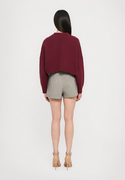 Burgundy lyhytvartalo sweater, jossa on pitkät hihat, yhdistettynä vaaleanharmaisiin raitashortseihin. Herkkä pinta, rento muotoilu, polvenpituudet shortsit.