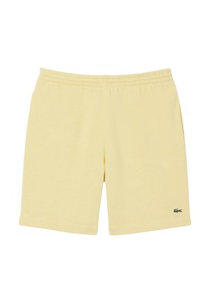 Shorts en coton jaune clair avec une taille élastique, des poches latérales et un petit logo vert sur l'ourlet gauche. Texture lisse, coupe décontractée.