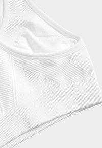 Reggiseno sportivo bianco con struttura a costine, design senza cuciture e scollo a dolce. Non presenta hardware o dettagli visibili.