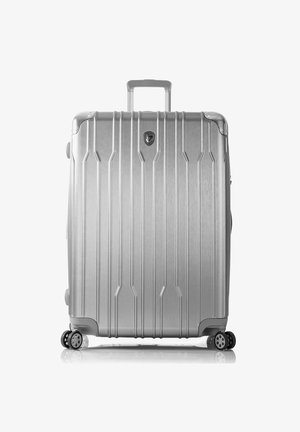Maleta rígida plateada con estrías verticales, asa integrada y cuatro ruedas. Cuenta con un logo y detalles metálicos para mayor durabilidad.