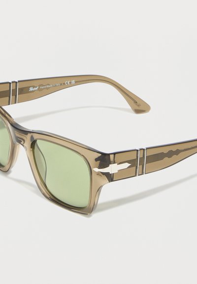 Rjave prosojne pravokotne sončna očala z zelenimi lečami in srebrnim kovinskim detajlom v obliki puščice na stranicah.