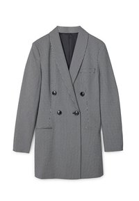 Blazer croisé en tissu pied-de-poule noir et blanc, doté d'un col à revers en pointe, de deux poches avant et d'une surface texturée.
