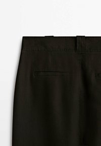 Vue arrière d'un pantalon noir montrant la ceinture, les passants de ceinture et deux poches passepoilées horizontales.