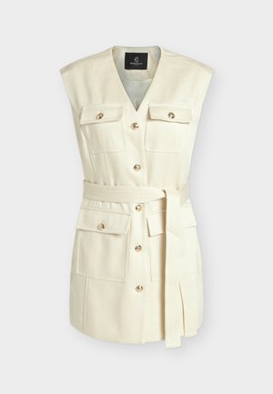 Prsluk bez rukava boje kreme s V-izrezom, četiri džepa s preklopom i gumbima, zlatni gumbi sprijeda i odgovarajući platneni remen vezan u struku.