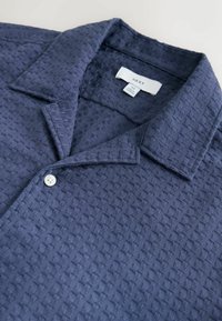 Navy short-sleeve shirt with a textured woven pattern, button closure, and a classic collar. Label visible inside collar.