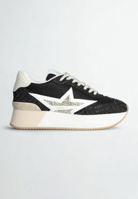 Baskets noires avec lacets blancs, une grande étoile blanche avec détails pailletés sur le côté, talon beige et semelle blanche épaisse avec semelle extérieure beige.