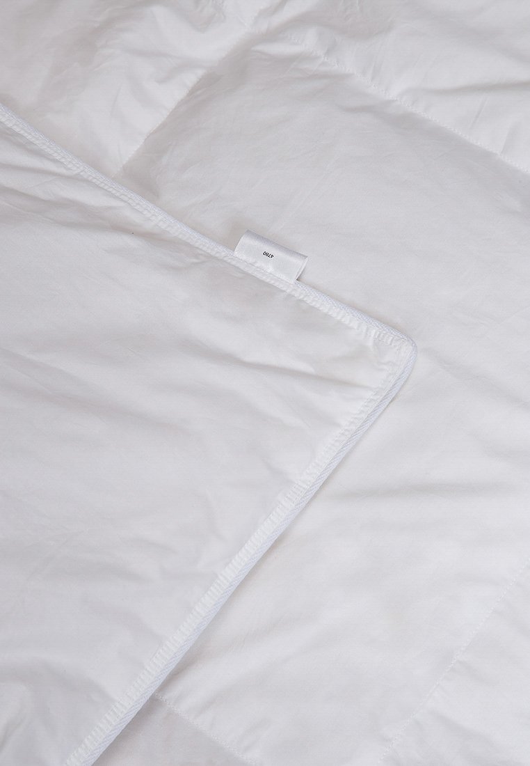 Weißer Bettbezug mit glatter Textur und dezentem Glanz. Verfügt über eine Paspelverarbeitung und ein kleines Etikett, das in die Ecke genäht ist.