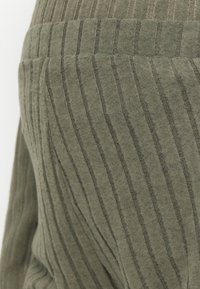 Teren fabric verde cu dungi, având o finisare moale și texturată. Liniile verticale de lățimi variate creează un model subtil. Potrivit pentru îmbrăcăminte casual.