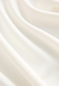Tela blanca suave con pliegues lisos y fluidos y sombras suaves que crean una sensación de textura y movimiento ligero.