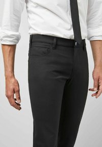 Zwarte slim-fit broek met een gladde textuur, voorzien van zijzakken, een op maat gemaakte tailleband en gestikte details aan de zijkanten.
