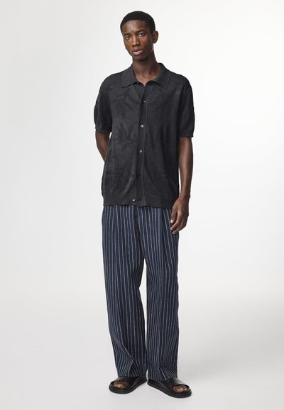 Zwart met patroon kortemouw hemden met een kraag, gecombineerd met marineblauwe gestreepte wijde broek en zwarte sandalen. Casual outfit met een relaxte pasvorm.