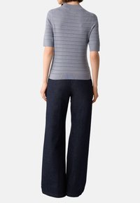 Hellgraues kurzärmliges Strickoberteil mit horizontalen Streifen und gerippter Textur, kombiniert mit weiten dunkelblauen Jeans.