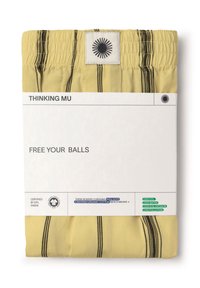 Gula boxershorts med svart randdesign, förpackade med en vit etikett som har miljöcertifieringsikoner och texten "FRIGÖR DINA KULOR."