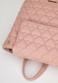 Bolso de mano de cuero acolchado en color rosa con un patrón de corazones, textura suave y herrajes en tono dorado. Incluye dos asas superiores para llevar.