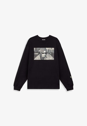 Schwarzes Sweatshirt mit langen Ärmeln, das einen großen Grafikdruck einer Person in Sonnenbrille und Mütze zeigt, mit Text in der unteren rechten Ecke.