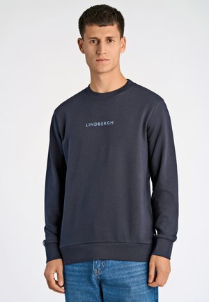 Sudadera de algodón azul marino con mangas largas, puños de canalé y cuello redondo. Presenta el texto "LINDBERGH" en azul claro en la parte frontal.