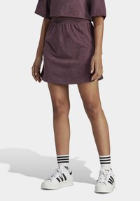 Lila mockasindress med elastiskt midjeband, matchad med vita sneakers med svarta ränder och matchande randiga strumpor.