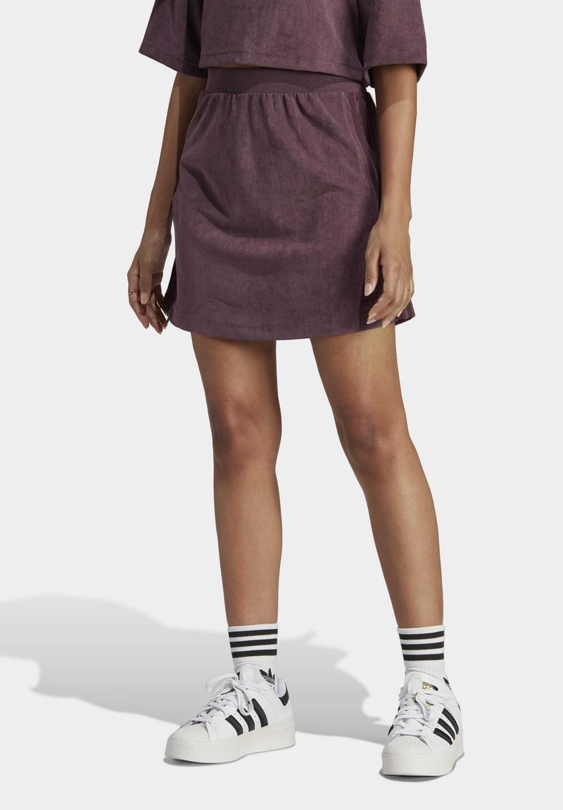 Lila mockasindress med elastiskt midjeband, matchad med vita sneakers med svarta ränder och matchande randiga strumpor.