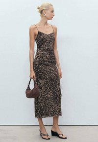 Haljina midi dužine s leopard uzorkom, prilagođenog kroja, s tankim trakama i nabranim detaljima, izrađena od lagane tkanine; uparena s smeškom torbicom i crnim sandalama.