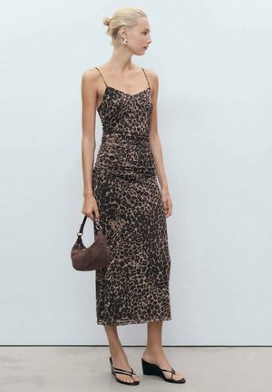 Robe midi ajustée à imprimé léopard avec des fines bretelles, détails froncés, fabriquée en tissu léger ; associée à un sac à main marron et des sandales noires.