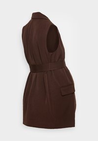 Manteau marron sans manches avec ceinture, col et poche à rabat latérale, coupe ajustée, présenté sur fond blanc.