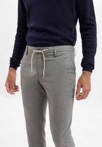 Pantaloni grigi a zigzag con vita regolabile. Realizzati in un morbido tessuto, presentano una vestibilità sartoriale e tasche laterali.