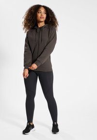 Mörkgrå zip-up hoodie med snörning, matchande svarta leggings och svarta sportskor. Slätt tyg med en figursydd design och långa ärmar.