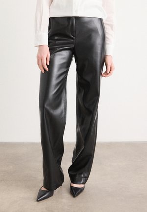 Pantalons en simili cuir noir avec une texture lisse, design large, plis à l'avant et taille haute. Assortis avec des talons aiguilles noirs.