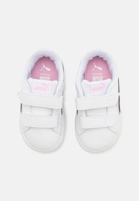 Weiße Kleinkind-Sneaker mit glatter Textur, schwarzen Akzenten und verstellbaren Klettverschlüssen. Sie verfügen über eine pinke Innensohle mit Branding.