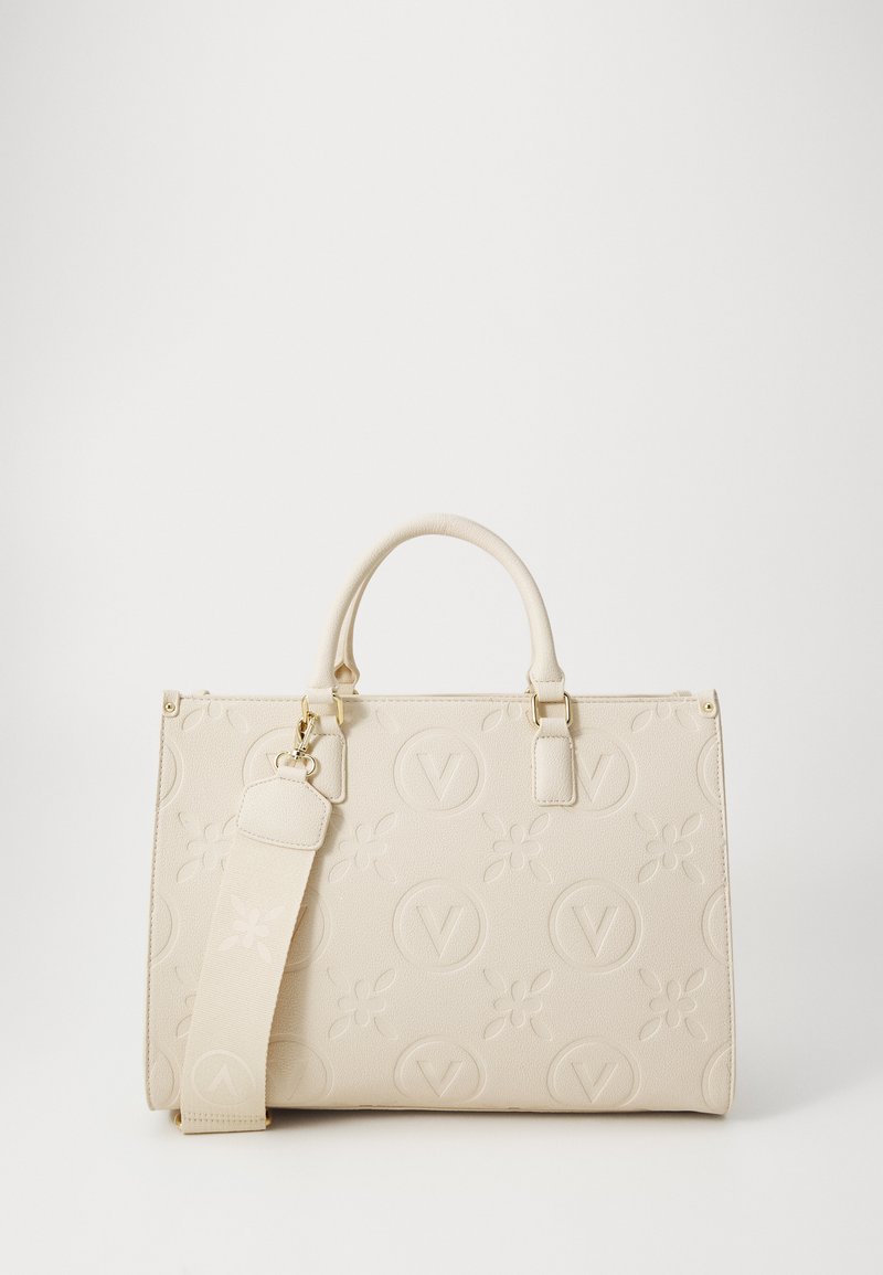 Sac à main beige avec un motif floral texturé, cercles en logo embossés, doubles poignées et une bandoulière amovible. Accents en métal doré.