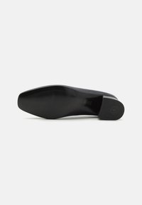 Svarte lærpumper med rund tå og lav, blokkhæl. Sålen har et teksturert mønster for grep. Rent, minimalistisk design.