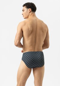 Niet-gevoerde zwemslips in donkerblauw met een geometrische print. Het ontwerp bevat onderling verbonden cirkels en een gladde, rekbare stof.