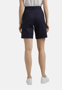 Pantalones cortos ajustados de color azul marino, confeccionados en tejido ligero, con una cintura alta, dos bolsillos traseros y un diseño de pierna recta.