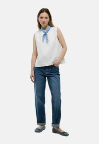 Haut sans manches blanc avec un col rond, écharpe à pois bleus, ballerines bleues et jeans bleus retroussés. Design simple avec une coupe décontractée.